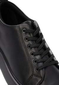 Black leather sneaker featuring a rounded toe, flat laces, metal eyelets, and a smooth finish with subtle stitching details on the side.
