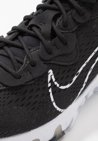 Black running shoe featuring a textured upper with perforations, black laces, and a white logo accent. Sole has a translucent detail.