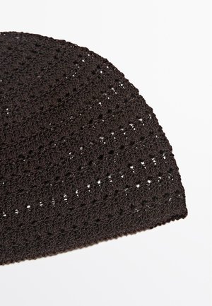 Primo piano di un tessuto nero lavorato a maglia o all'uncinetto con un disegno texturizzato e decorato su sfondo bianco.