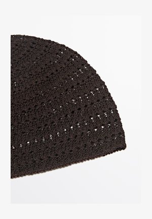 Primo piano di un tessuto nero lavorato a maglia o all'uncinetto con un disegno texturizzato e decorato su sfondo bianco.