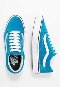 Modré semišové tenisky s bílými tkaničkami a detaily. Mají výrazný boční pruh a polstrovaný vnitřek s puntíkovanou podšívkou.