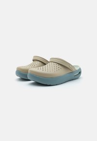 Light brown clogs with perforated design and a teal rubber base. Features a back strap and rounded edges for comfort and ease of wear.