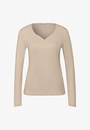 Top beige a maniche lunghe e scollo a V realizzato in cotone morbido. Presenta un design aderente e una leggera cucitura decorativa lungo l'orlo e le maniche.