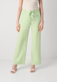 Světle zelené lněné široké kalhoty s elastickým pasem, vyznačující se hladkou texturou a uvolněným střihem. Ozdobeno stříbrným kováním.