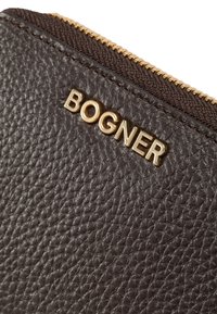 Portafoglio in pelle marrone con superficie testurizzata, caratterizzato da un logo dorato "BOGNER" e una cerniera in tessuto scuro.