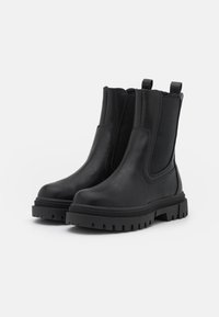 Botas Chelsea negras de cuero suave, con paneles laterales elásticos, tiradores, suela resistente y un diseño de punta redondeada.