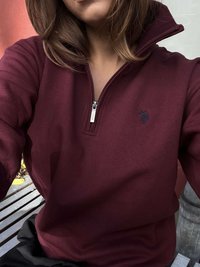 Bordo jopa z zadrgo iz mehkih materialov; ima visok ovratnik, subtilno vezenje logotipa in rebraste manšete. Postavljeno na nevtralno ozadje.