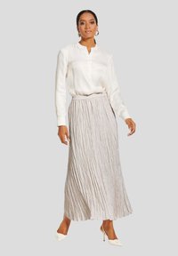 Witte blouse met knopen, gecombineerd met een lichtgrijze, geplooide maxi-rok. De rok heeft een gestructureerde afwerking en een elastische tailleband.