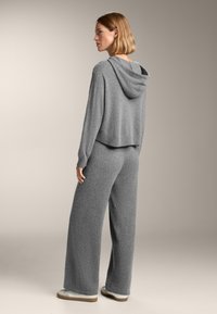 Set di abbigliamento loungewear grigio composto da un top corto in stile hoodie con una vestibilità rilassata e pantaloni a gamba larga, realizzato in un morbido tessuto testurizzato.