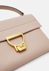 Light beige leather handbag with a textured finish, featuring a prominent gold-tone clasp and a slim strap attached.