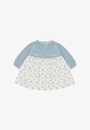 Vestido para bebé de manga larga con parte superior de punto azul y falda blanca decorada con pequeños patrones de árboles marrones y grises.