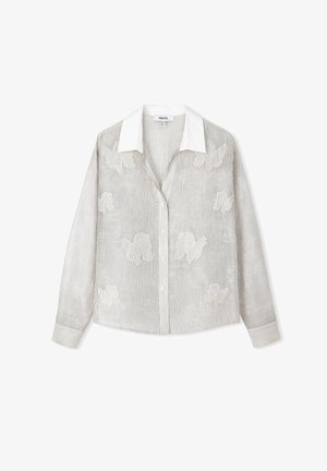 Chemise rayée en gris clair avec des broderies florales blanches. Dotée d'un col et de poignets blancs, fermeture à boutons et manches longues.