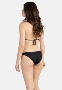 Ensemble bikini noir comprenant un haut à nouer dans le dos et un bas taille basse. Tissu lisse et extensible avec une couvrance minimale et un design simple.