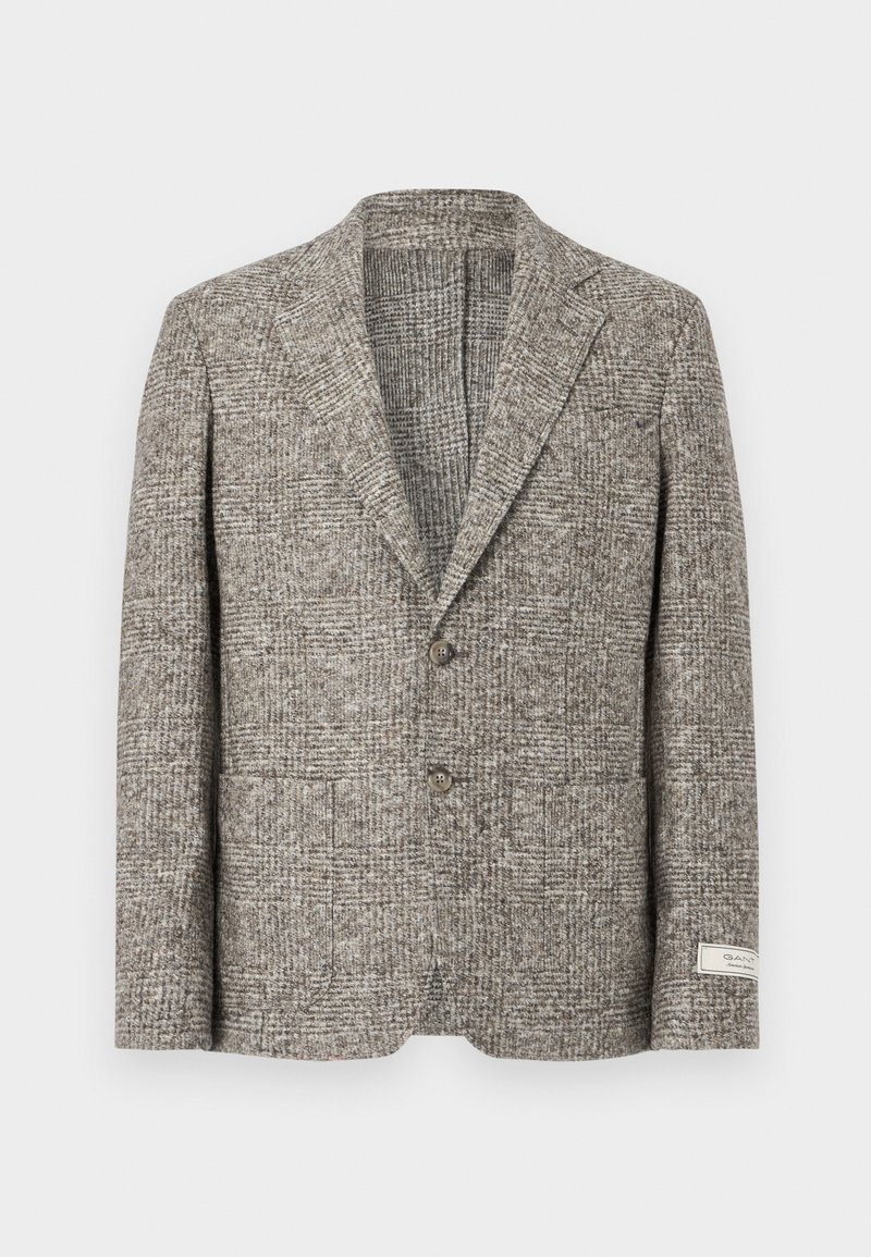Wollen blazer in een getextureerd bruin ruitpatroon. Kenmerkt zich door een notched lapel, twee voorzakken en twee knopen. Label op de linkermouw.
