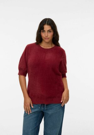 Burgunderfarbener, flauschiger Pullover mit kurzen Ärmeln und rundem Halsausschnitt, kombiniert mit lässigen blauen Denim-Jeans, die eine strukturierte Oberfläche aufweisen.
