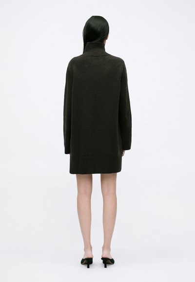 Σκούρο πράσινο, υπερμεγέθες πλεκτό φόρεμα-σουέτερ με ψηλό γιακά, ραμμένες μανσέτες και τελείωμα. Λείος σχεδιασμός, μήκος μέχρι το μέσο μηρού και χαλαρή εφαρμογή.