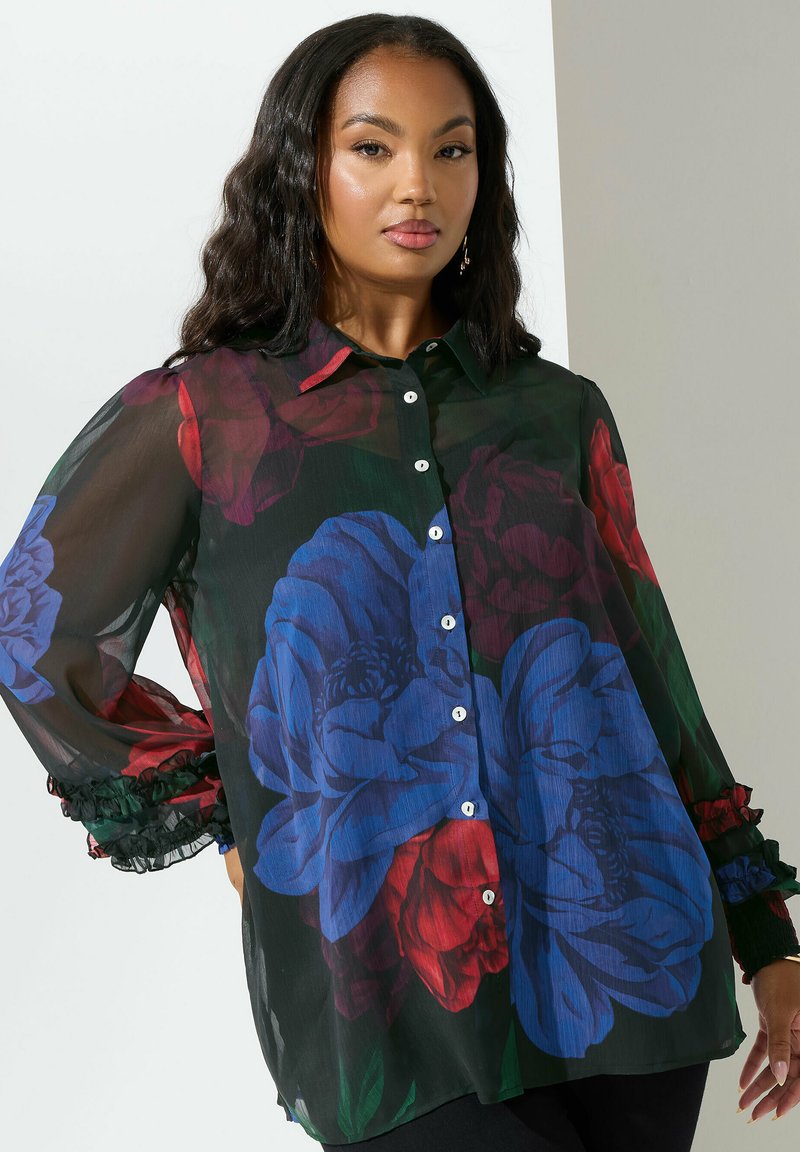 Camicia nera trasparente con grandi stampe floreali blu e rosse, bottoni frontali, colletto e polsini arricciati, realizzata in tessuto leggero.