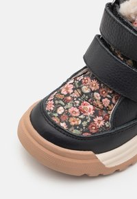 Czarne skórzane buty z górą z floralnej tkaniny, z rzepami i gumową podeszwą w jasnobrązowym kolorze. Teksturowane wykończenie wzdłuż krawędzi.