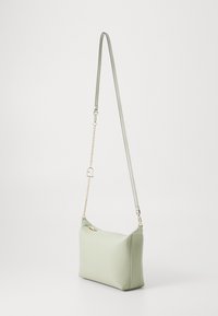 Borsa a spalla strutturata di colore verde chiaro, realizzata in ecopelle. Dotata di catena e tracolla removibili, texture liscia e design minimalista.
