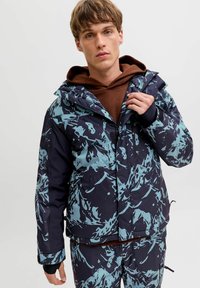 Giacca invernale blu e navy con motivo, dotata di cappuccio, chiusura con zip, tasche frontali e rivestimento interno marrone a contrasto.