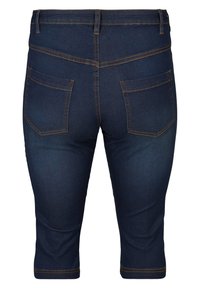 Temno modri denim capri hlače s prilegajočo obliko, vidnim oranžnim šivanjem, dvema zadnjima žepoma in srednje visokim pasom.