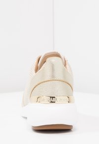 Helle rosa Sneaker mit strukturierten goldenen Akzenten und einer weißen Sohle. Verfügt über eine metallische Logo-Platte an der Ferse und ein Obermaterial aus Mesh.