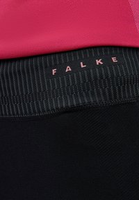 Zwarte sportleggings met een gestructureerde tailleband met een subtiel gestreept patroon en een roze "FALKE"-logo. Glad, rekbaar materiaal.