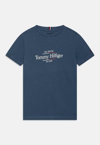 Námorně modré tričko vyrobené z bavlny, s kulatým výstřihem a krátkými rukávy. Přední grafika obsahuje "New York City" a "Tommy Hilfiger."