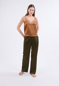 Camisón de satén marrón con detalles de encaje, combinado con pantalones de pijama verdes con un patrón de flores. Corte relajado, tejido ligero.