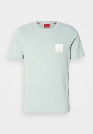 Hellgrünes Baumwoll-T-Shirt mit Rundhalsausschnitt, kurzen Ärmeln und einer kleinen weißen aufgesetzten Tasche mit dem Markenlogo. Roter Krageninnenbereich.