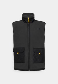 Gilet in pile grigio scuro con colletto alto, zip frontale e due tasche nere trapuntate con dettagli gialli. Presenta un logo sul petto.