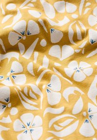 Gult tyg med en slät yta, med ett upprepande mönster av vita blommor som har blå detaljer.