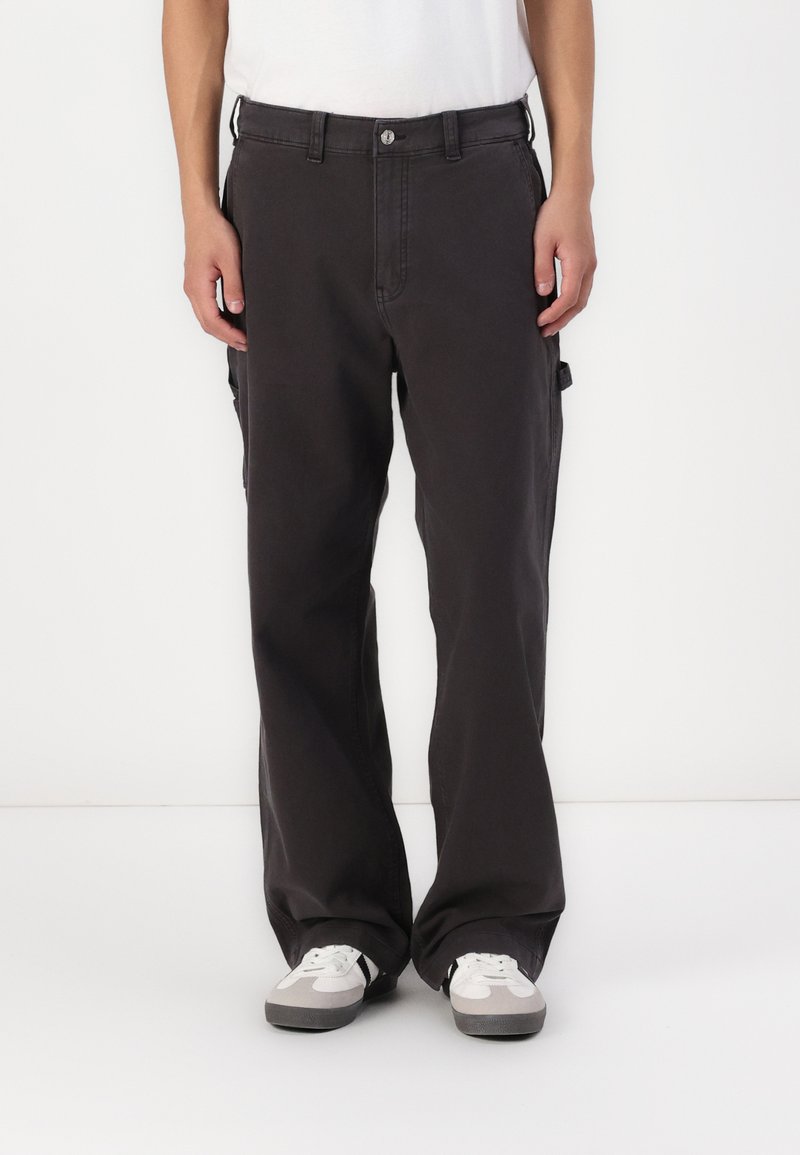 Pantaloni cargo negri cu un design drept, având buzunare laterale, închidere cu nasture și o textură de țesătură rezistentă. Purtați cu adidași gri.