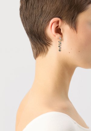 Gold-tone drop earrings feature a cascading design with oval and round gemstones in various colors, enhancing their intricate arrangement.