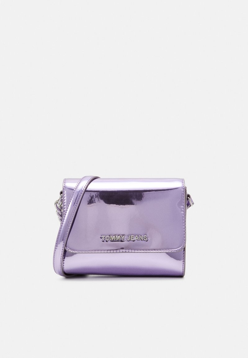 Fialová metalická crossbody taška s klopovým zavíráním. Na přední straně se nachází stříbrné logo "TOMMY JEANS" a odnímatelný stříbrný řetězový popruh.
