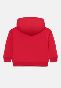 Bakvy av en vanlig röd hoodie med långa ärmar och ribbade muddar och fåll.