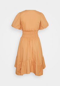 Vista trasera de un vestido naranja de longitud hasta la rodilla, de manga corta, con cintura fruncida y dobladillo con volantes sobre un fondo neutro.