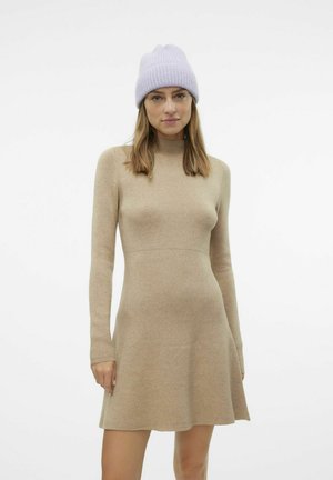 Gebreide tan jurk met lange mouwen, hoge hals en vloeiende zoom. gedragen met een lichtpaarse geribbelde beanie. Soepele textuur, minimalistisch ontwerp.
