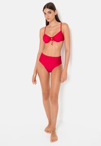 Red bikini set featuring a bow detail on the top and high-waisted briefs. Smooth fabric with a solid color. Adjustable straps.