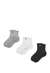 Tre par sokker: to grå, en hvid, en sort. De har ribbede manchetter og et cirkulært logo på siden. Materiale i bomuldsblanding.