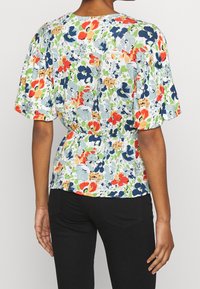 Halenka s květinovým potiskem, krátkými rukávy, elastickým pasem a kombinací červené, modré, zelené a oranžové na světlém pozadí.