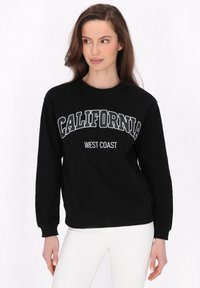 Fekete pulóver fehér "CALIFORNIA" és "WEST COAST" felirattal. Kerek nyakkivágással és hosszú ujjakkal készült, puha, texturált anyagból.
