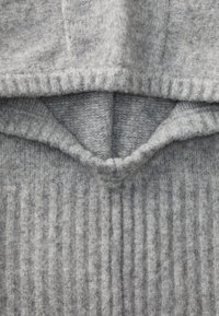 Sweter cinza de malha com uma superfície macia e texturizada. Apresenta um design canelado na parte inferior e uma seção superior suave.