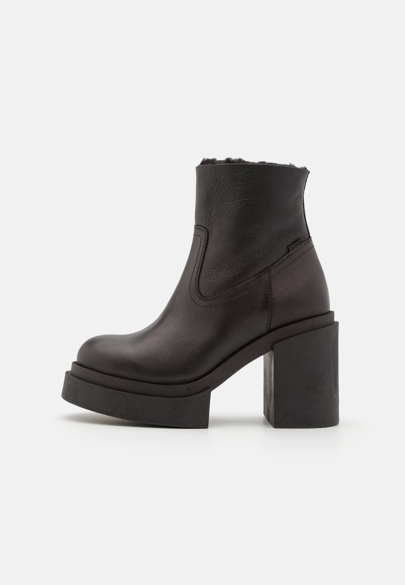 Bottine noire en cuir avec talon haut épais bloc et semelle plateforme, présentant un bout arrondi et une tige lisse.