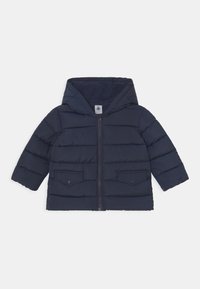 Donkerblauwe pufferjas met capuchon, ritssluiting aan de voorkant en twee borstzakken. Heeft een doorgestikt ontwerp en een gladde textuur voor isolatie.