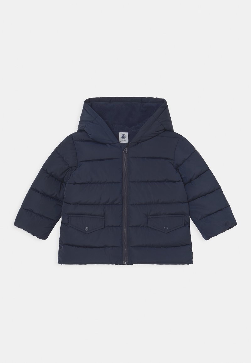 Donkerblauwe pufferjas met capuchon, ritssluiting aan de voorkant en twee borstzakken. Heeft een doorgestikt ontwerp en een gladde textuur voor isolatie.