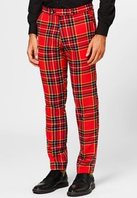 Red plaid trousers with black and yellow accents, featuring a straight leg design. Worn with a black shirt and shiny black shoes.