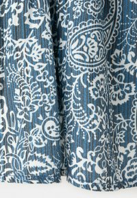 Blauer Stoff mit weißen, filigranen floralen und Paisley-Mustern sowie dezenten vertikalen Streifen, dargestellt in sanften Falten.