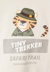 Kreslený tiger v zelenej safari čiapke a bundě nad textom: "Malý objaviteľ Safari Trail Okavango Delta."