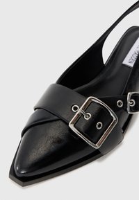 Black pointed-toe slingback shoe made of leather, featuring a wide strap with a silver buckle detail for adjustment.